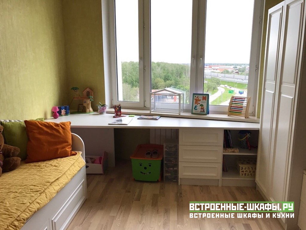 Письменный стол у окна с балконом в детской