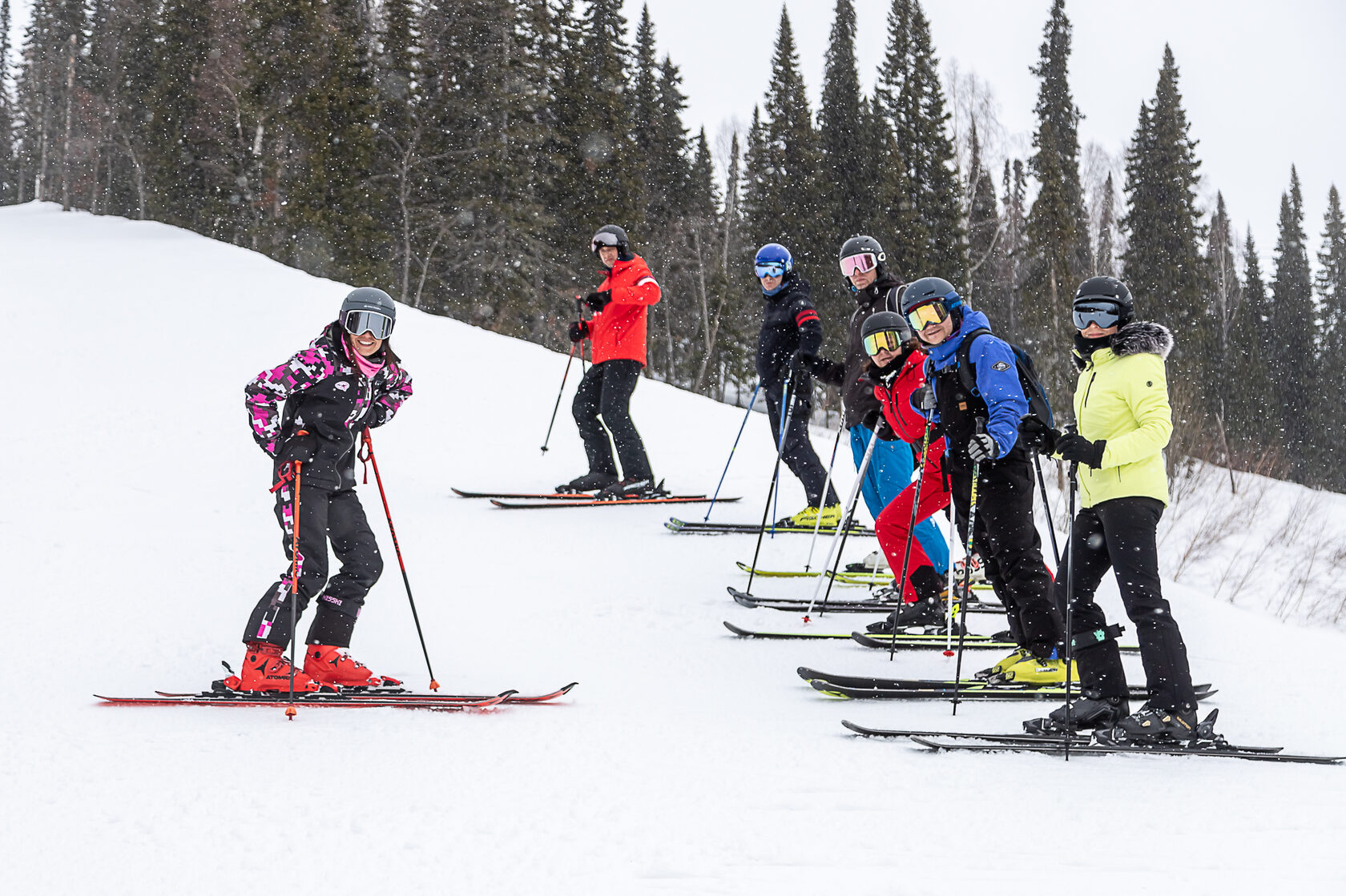 Основатель школы горных лыж Discoride мастер спорта Лиза Манькова в процессе обучения учеников на фоне горнолыжного склона и елей