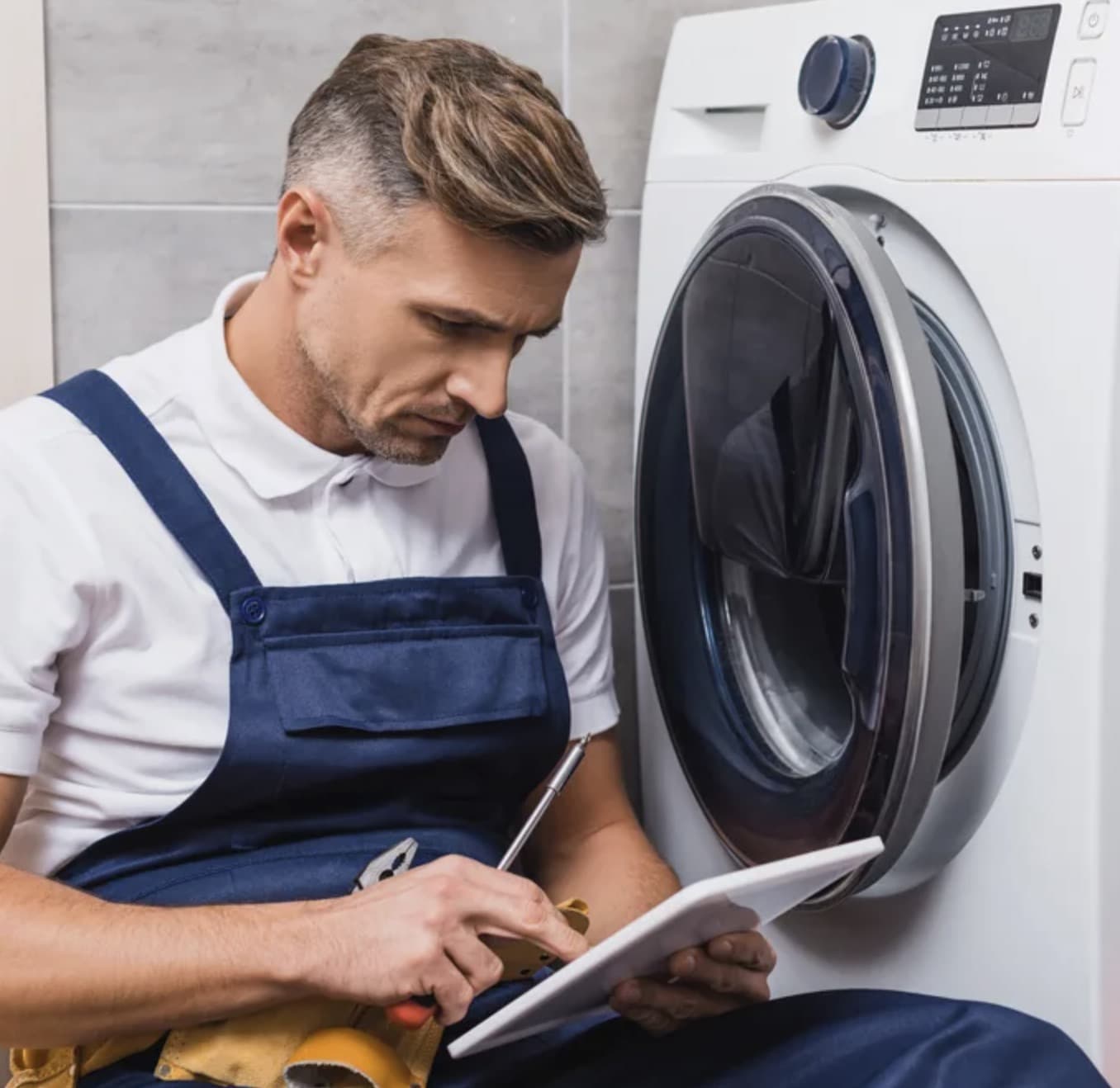 Мастер ремонтирует стиральную машину