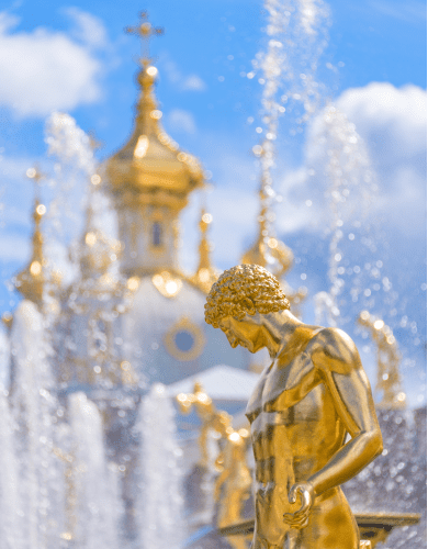 A fountain with gilded sculptures in Peterhof and a church on the background