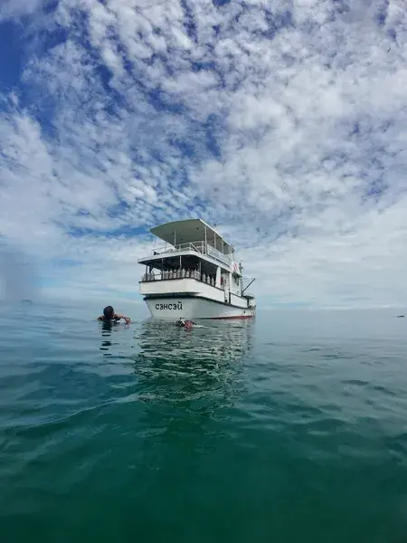 Катер в море, рядом двое в воде