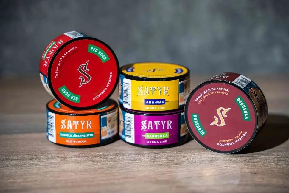 A close-up of colorful tins of Satyr shisha tobacco, including flavors like Red Hood and Babushka, among the top best tobaccos for your shisha for advanced smokers.