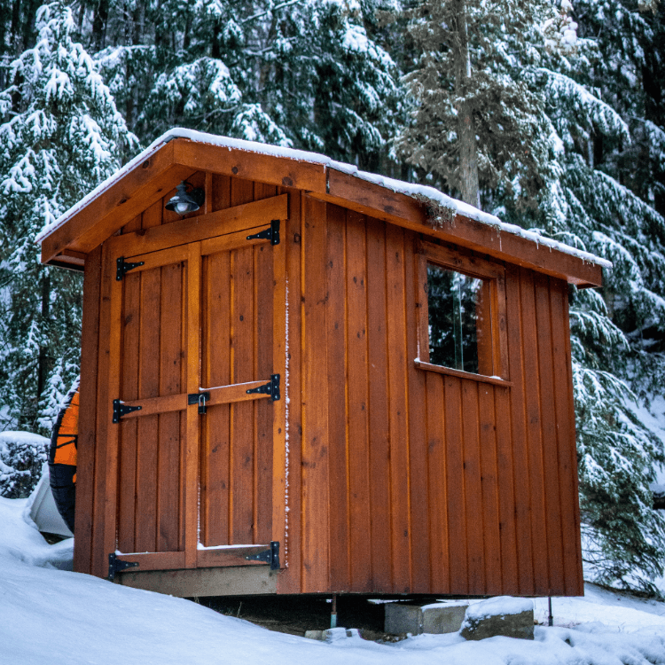 Ein klassisches Saunahaus in der Form eines Gartenhauses in einer verschneiten Landschaft