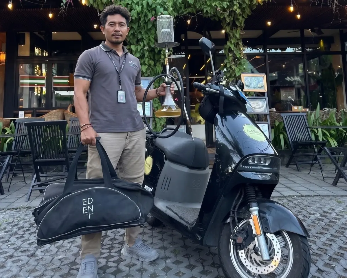 A friendly GoShisha specialist arriving on a scooter with premium hookah equipment, ready for a seamless shisha delivery in Bali.