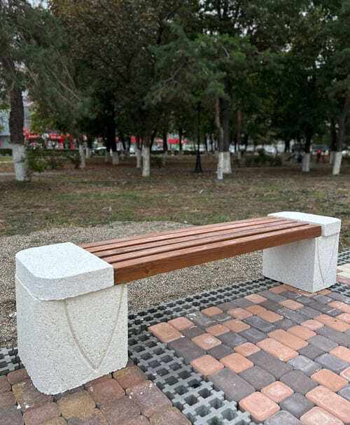 Длинная скамейка из деревянных реек и с большими белыми мраморнми ножками