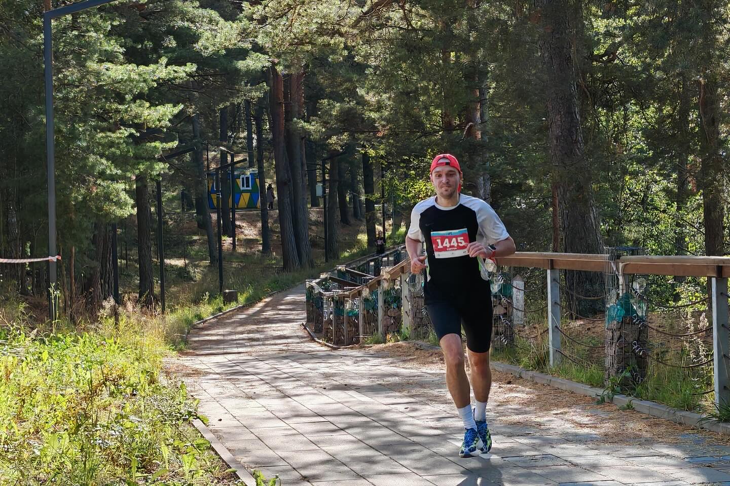 Бегун на пробежке выполняет задание по тренировочному плану в парке Петербурга
