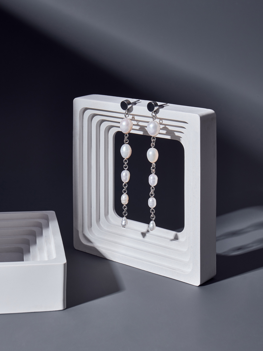 свисающие серьги на камне серый фон студийная съемка