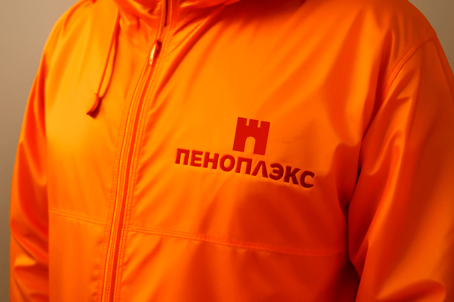 Оранжевая ветровка с логотипом Пеноплэкс — пример корпоративного подарка