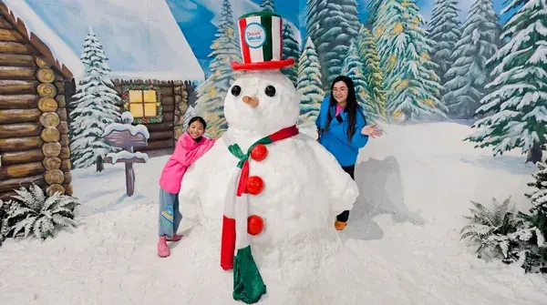 Снеговик в красной шляпе и гости в снежном городе Snow Town парка Dream World