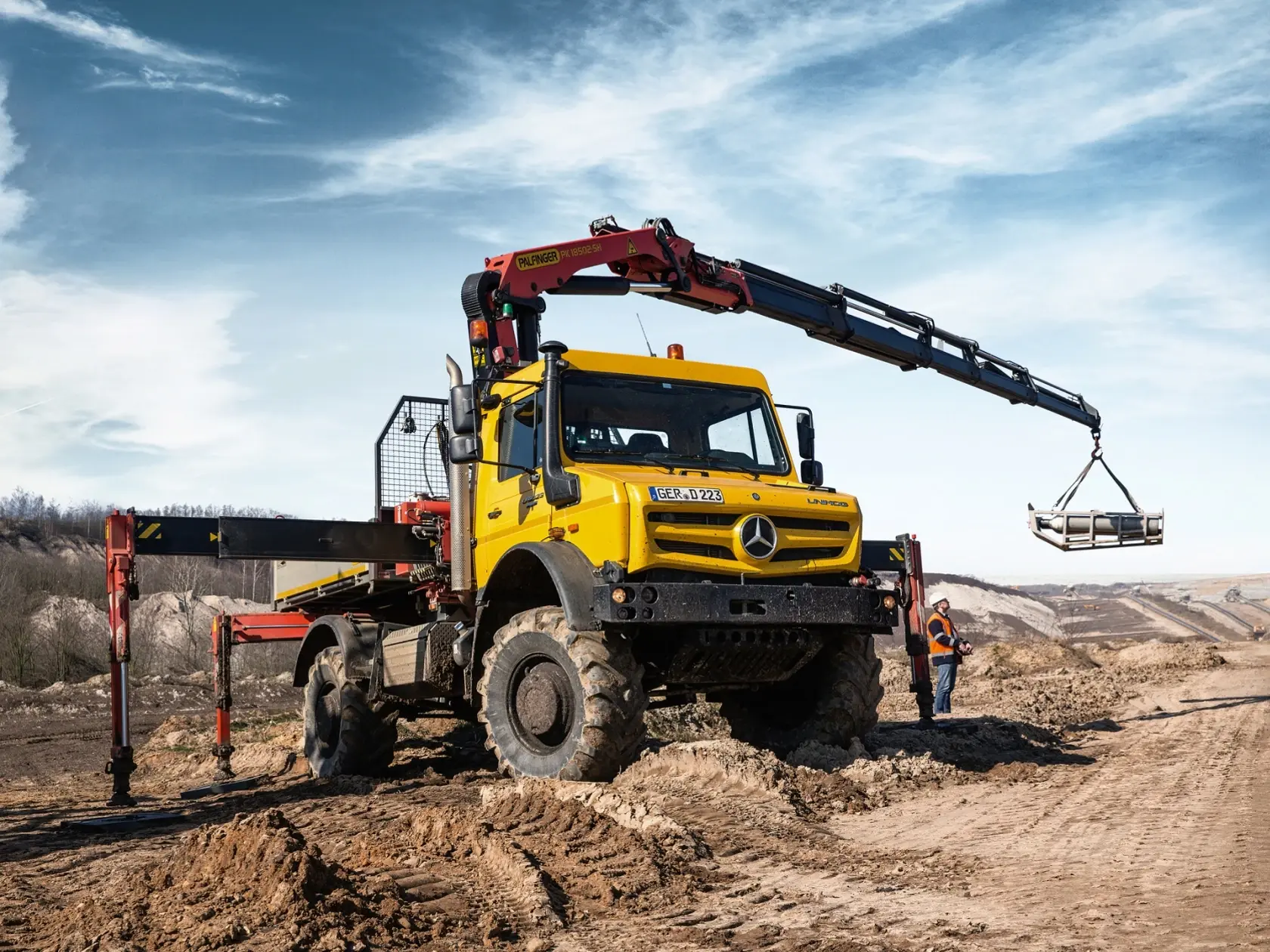 Жёлтый Unimog с краном-манипулятором на песчаном карьере