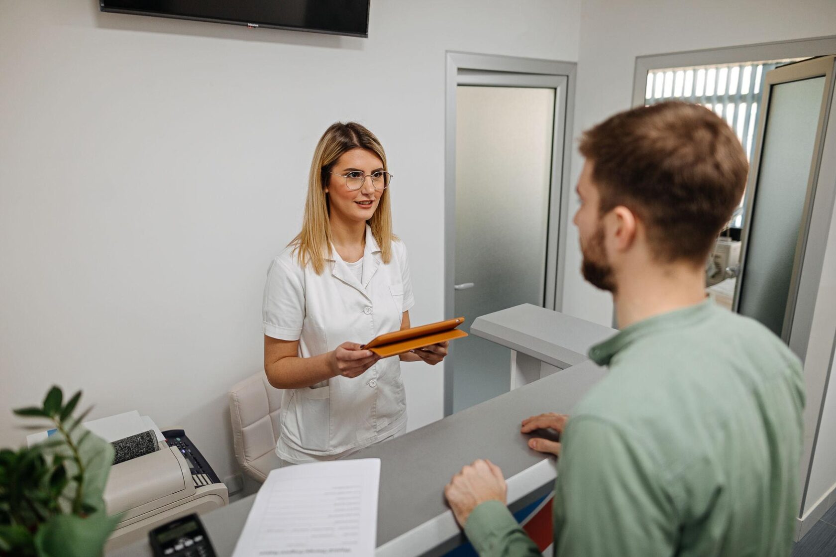 Female receptionist talking with patient in medical clinic