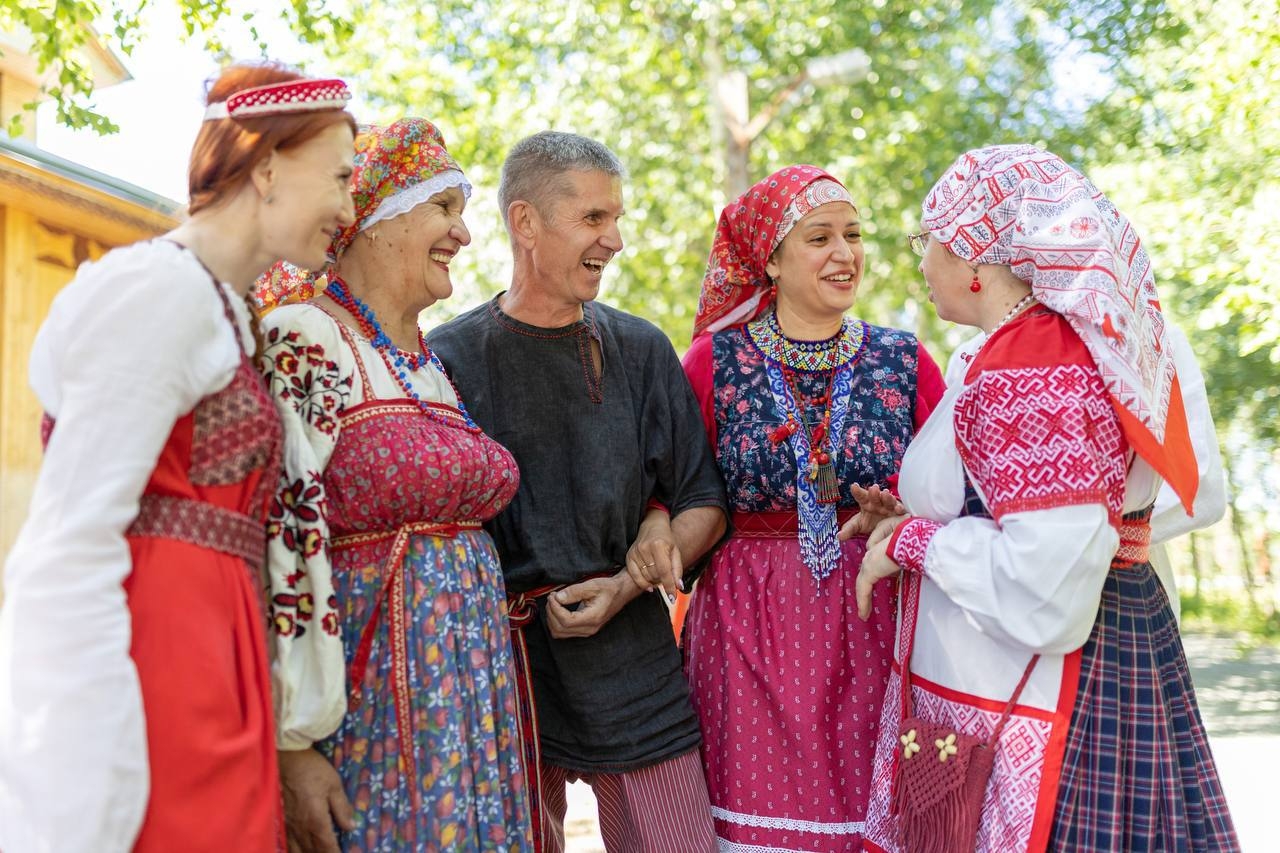 Woman in a red folk costume sitting beside a man playing the accordion