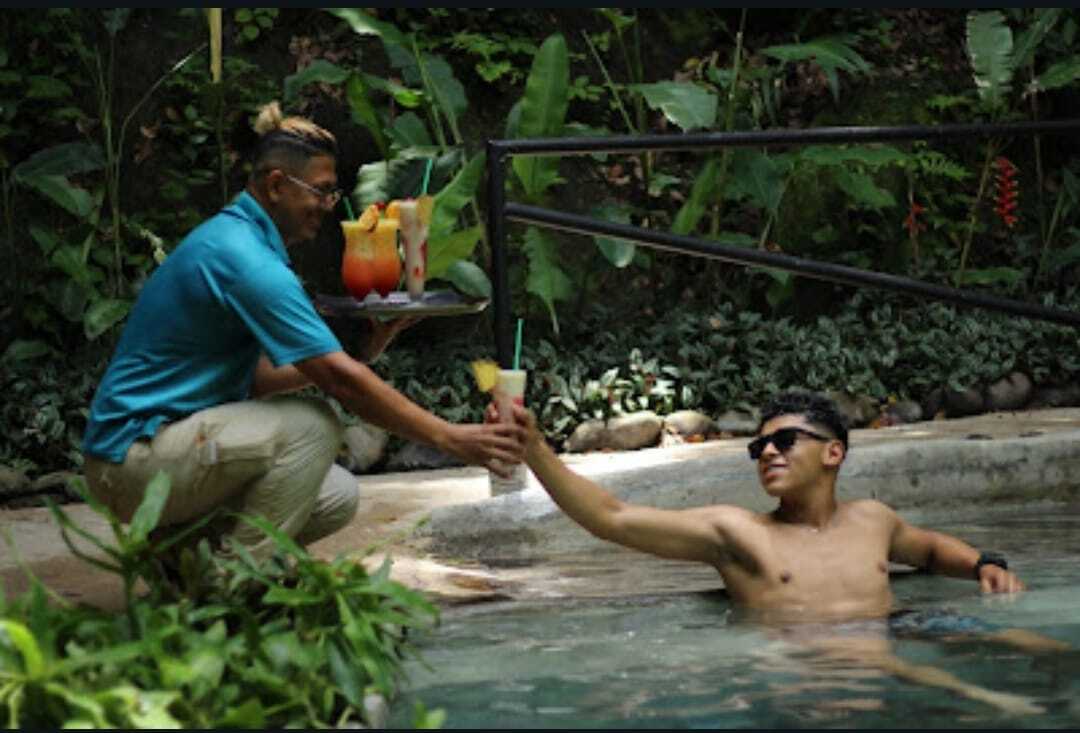 Guest relaxing in an outdoor pool surrounded by tropical plants