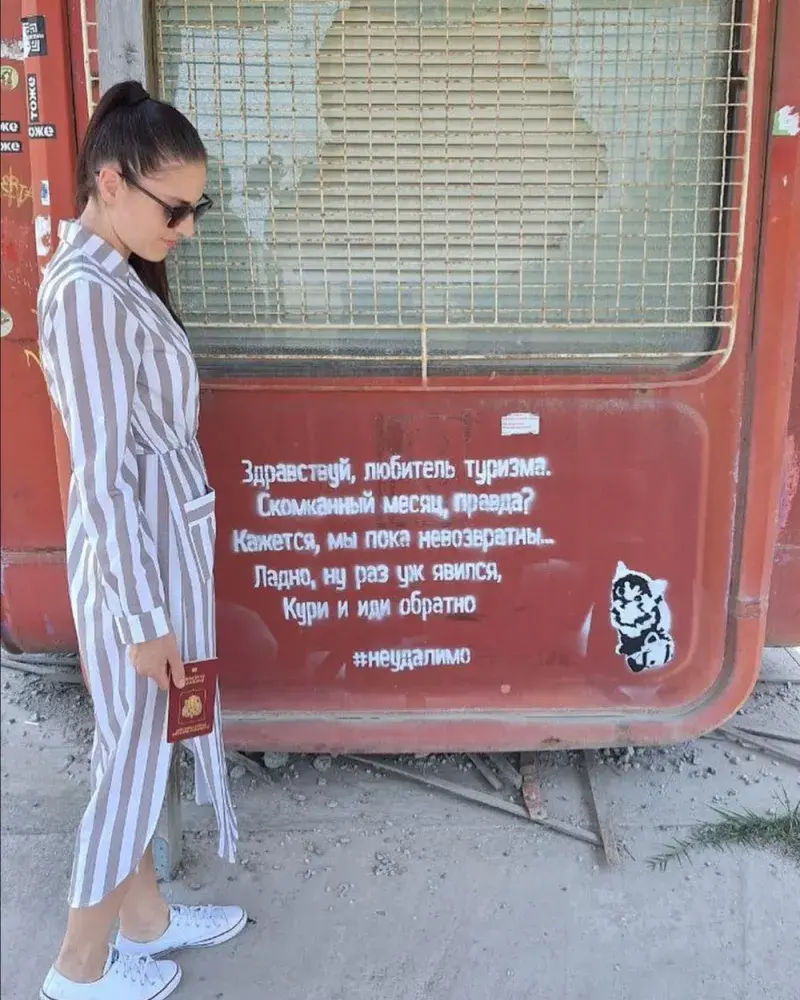 A visitor holding a passport beside the poem