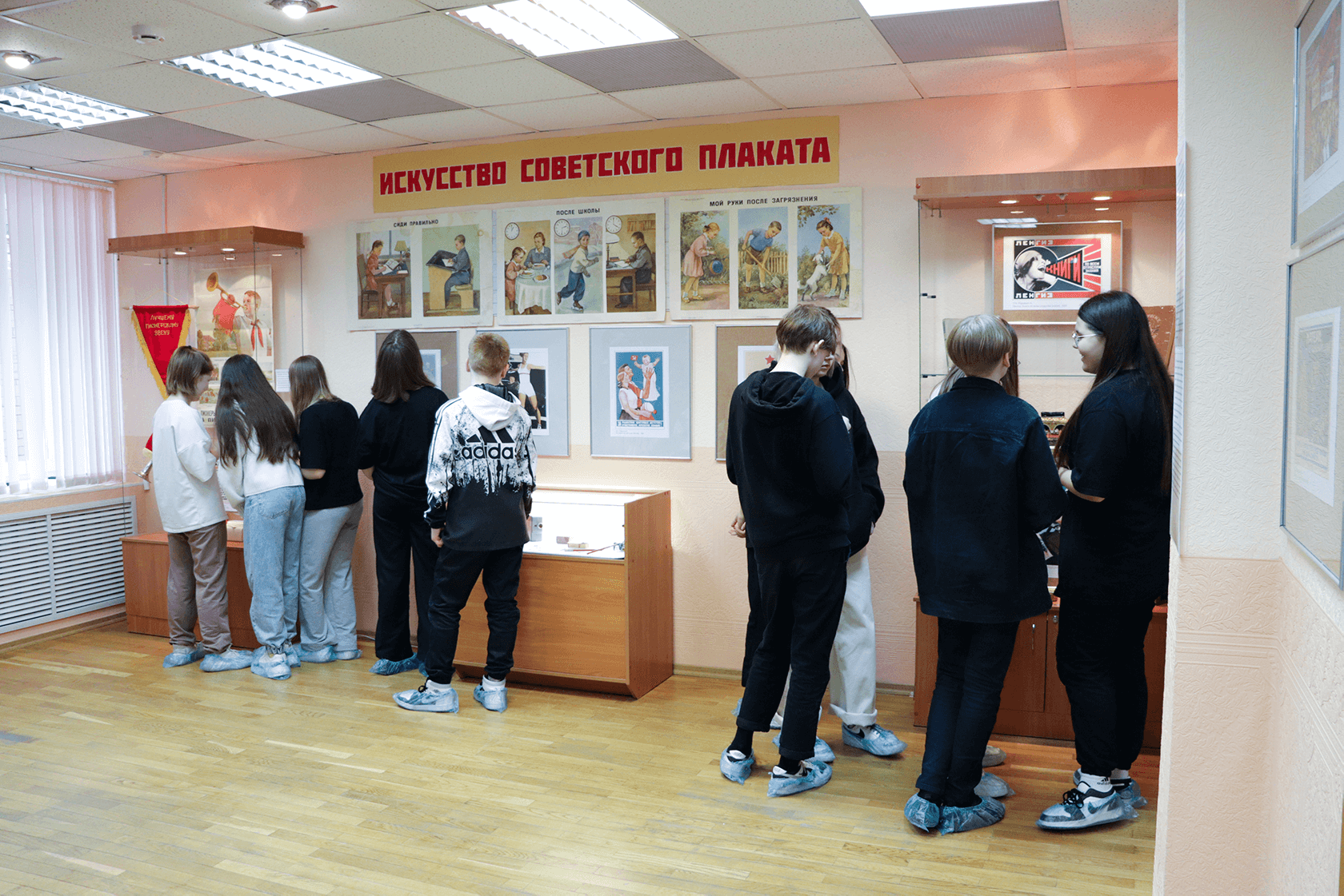 подростки рассматривают предметы на выставке «Искусство советского плаката»