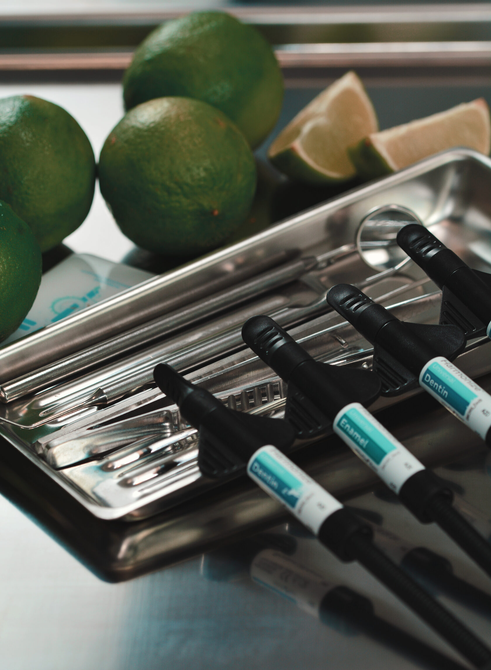 стоматологический лоток, на котором лежат лаймы и стоматологические пломбировочные материалы