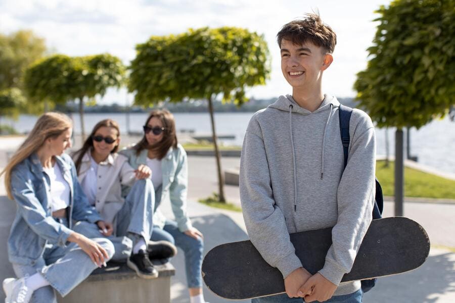 На картинке изображены подростки, на переднем плане парень, на заднем плане три девушки