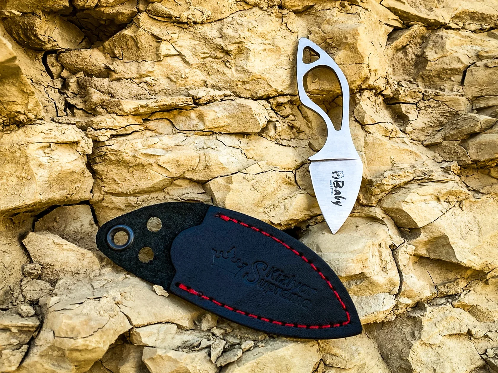 Kizlyar Supreme Baby knife and leather sheath on warm stone
