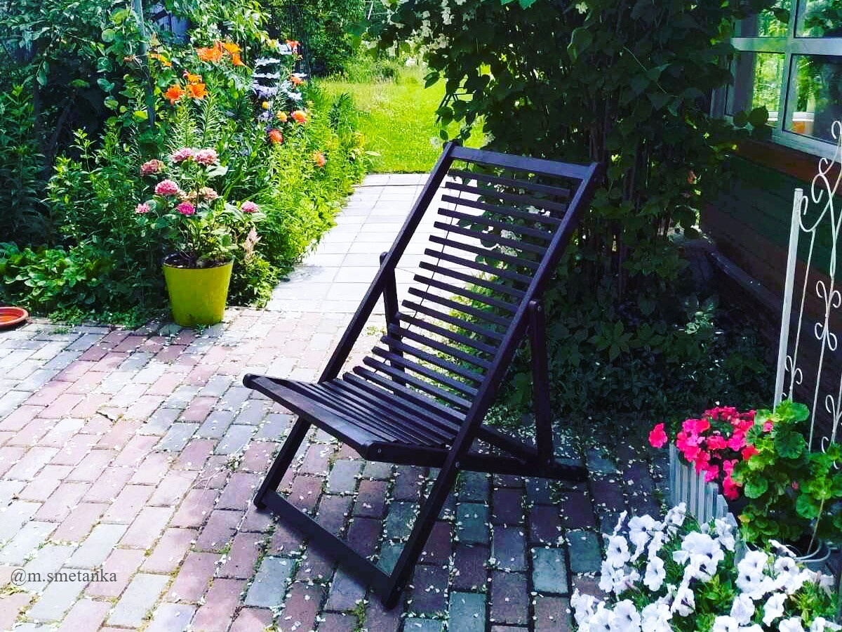 цветы и деревянный шезлонг в саду
