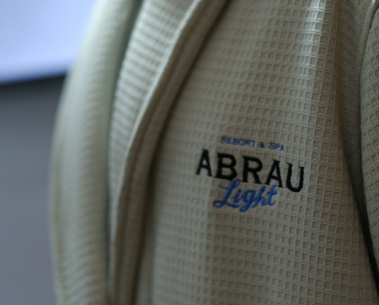 Вышитый логотип отеля Abrau Light крупным планом на вафельной ткани халата