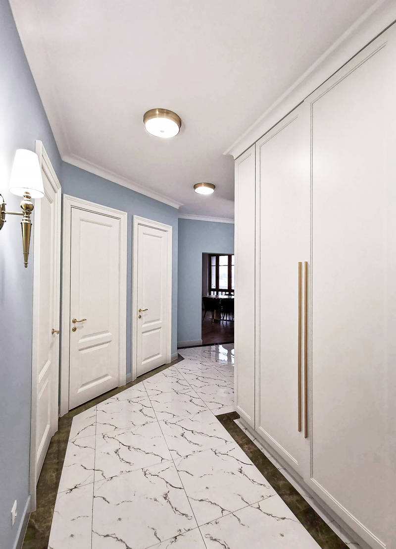 белый шкаф от пола до потолка с латунными ручками, белая плитка на полу с имитацией мрамора, коричневый кант, бра