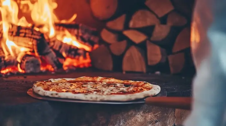 Freshly baked pizza served near a traditional wood-fired oven