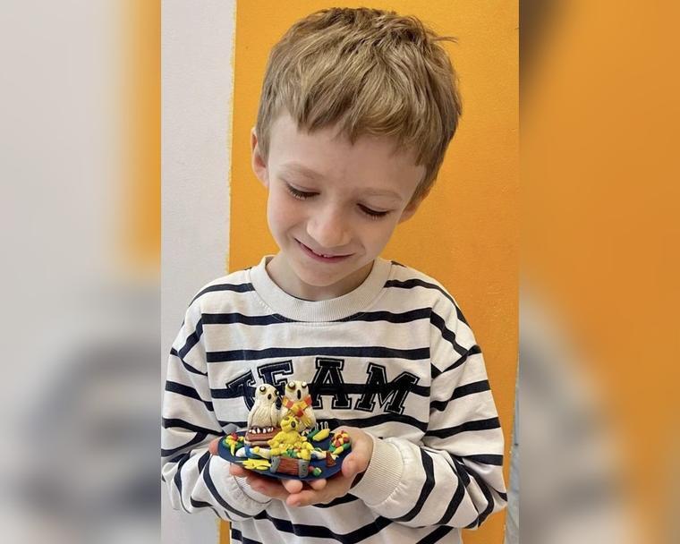 Мальчик с пластилиновой композицией с совами, сделанной на занятии лепкой