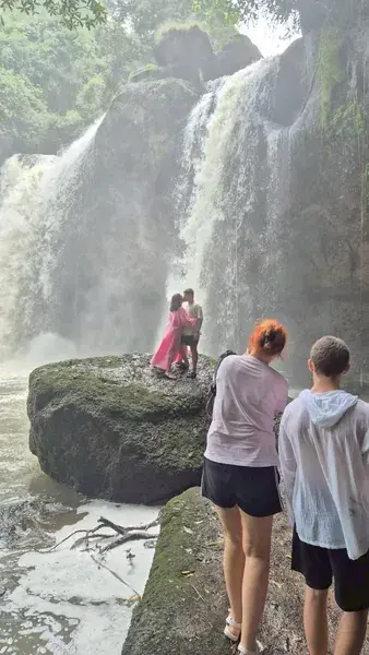 Туристы у мощного водопада в брызгах