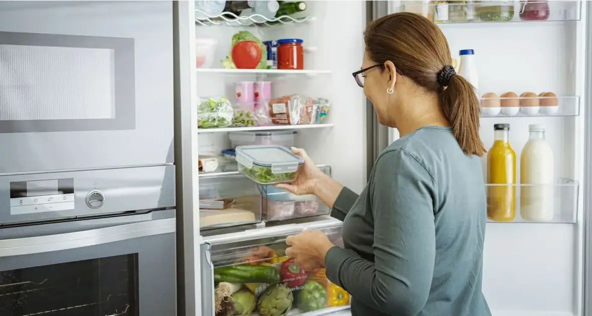 Женщина смотрит в холодильник