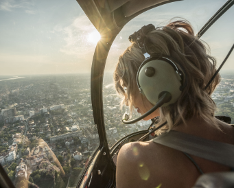 Девушка в вертолете летит над городом