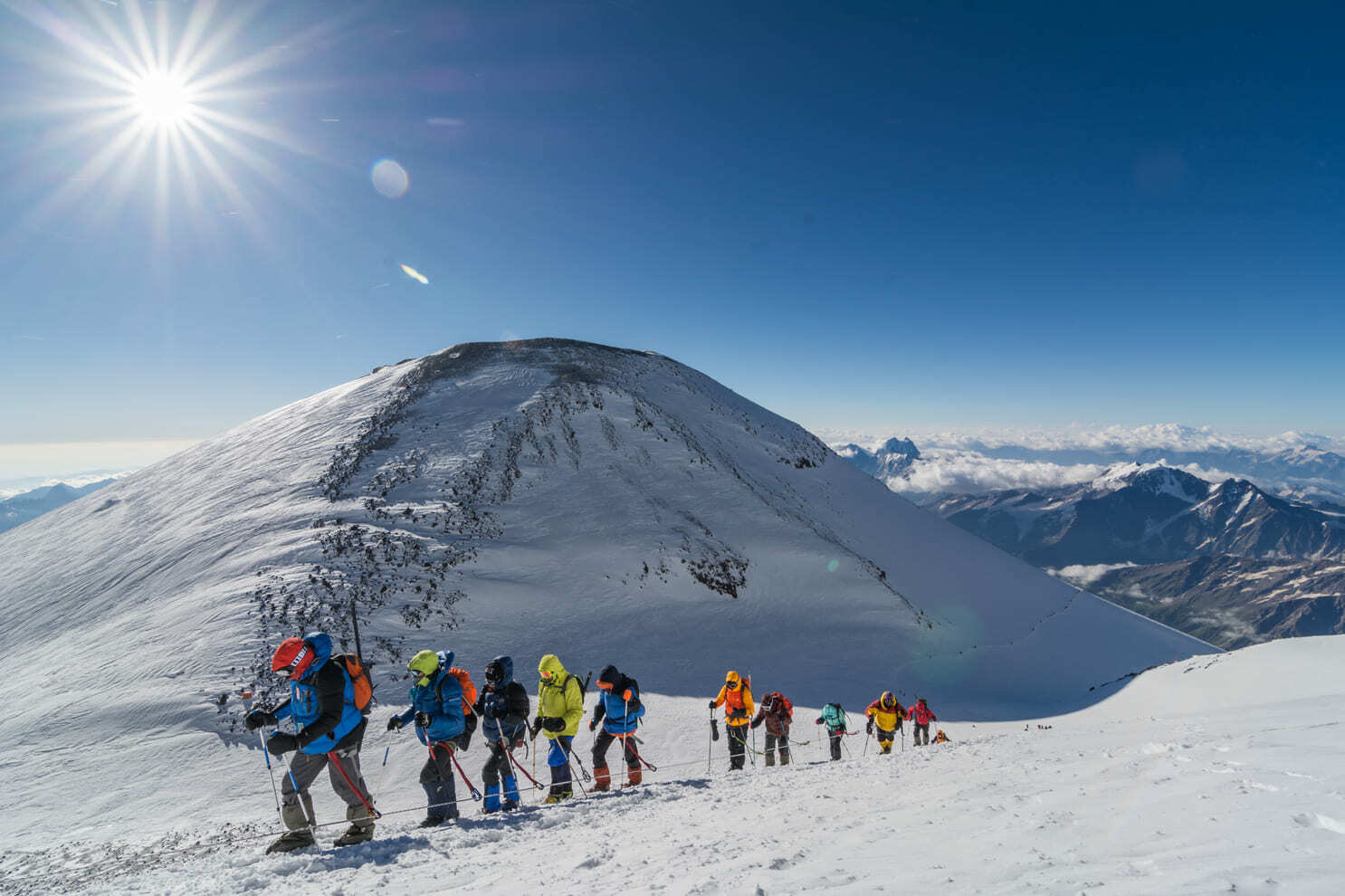 Line of climbers on the sunlit upper snow slopes of Elbrus