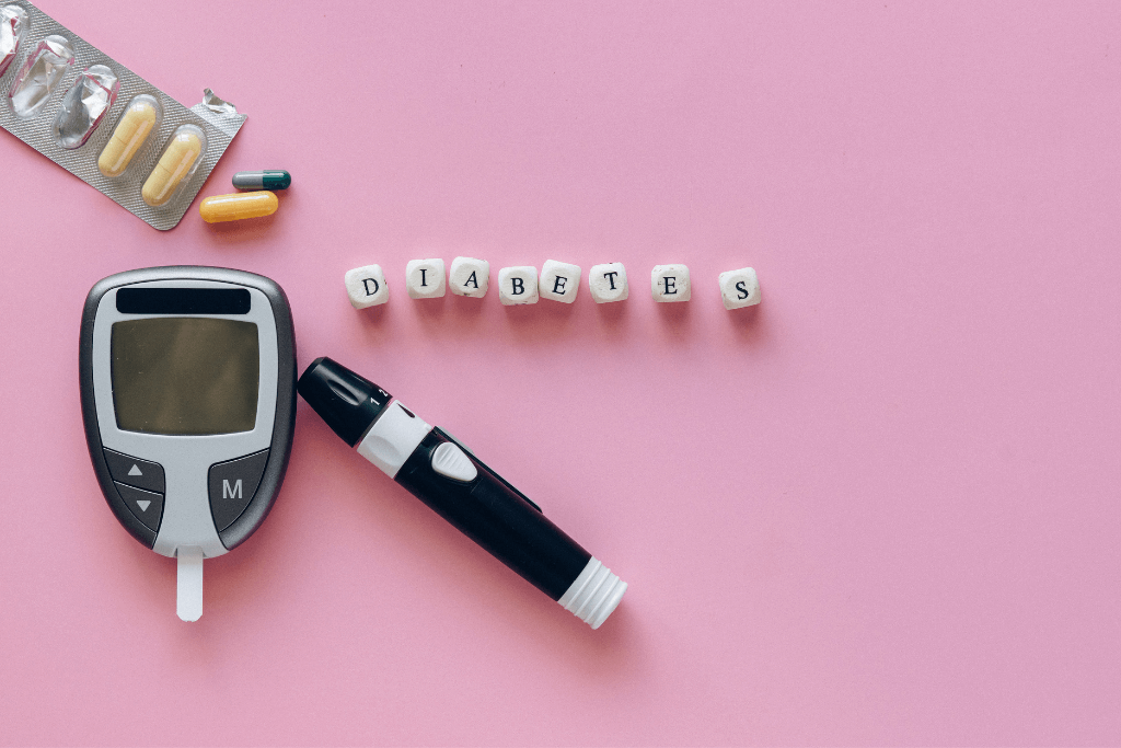 Blutzucker-Messgerät, Medikamente, Insulinpen und bedruckte Würfel die das Wort Diabetes ergeben