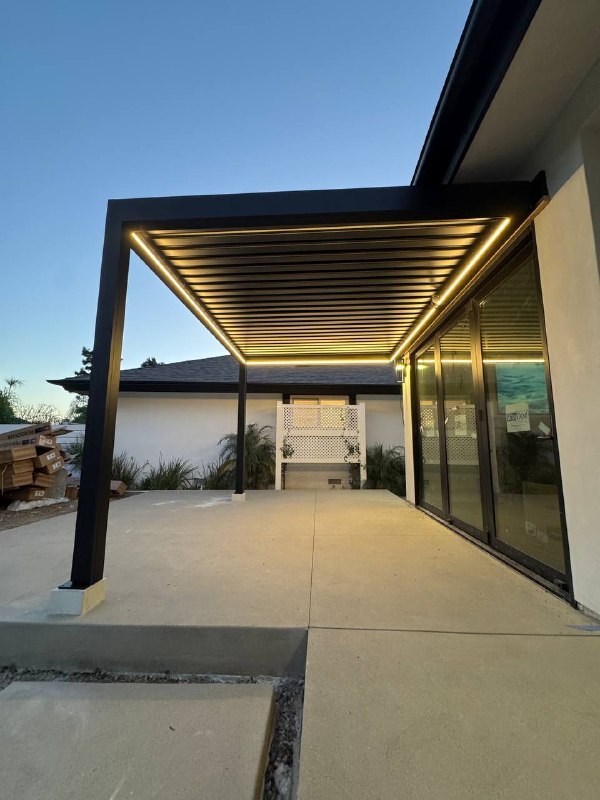 View beneath the pergola with illuminated perimeter LED strips and a blue evening sky.