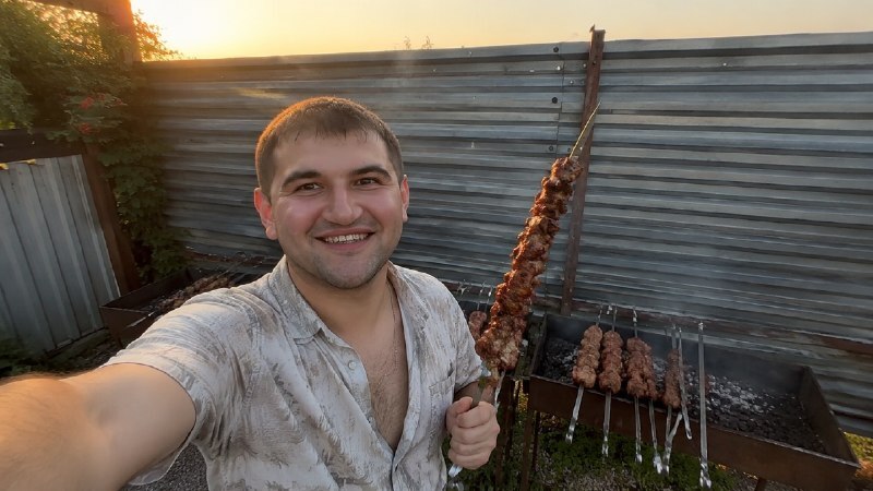 Мужчина с шашлыками стоит у мангалов на территории гостевого дома Семья в Должанке