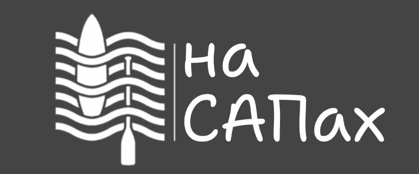 A sunny, vibrant scene of a SUP (stand-up paddleboard) rental station along the banks of the Neva River in St. Petersburg, Russia. The foreground features an array of colorful SUP boards lined up on the dock, with a friendly staff member assisting customers. The middle ground showcases the iconic St. Petersburg architecture, with the ornate Church of the Savior on Spilled Blood in the distance. The background is filled with a panoramic view of the city's historic cityscape, with the Neva River flowing calmly. The lighting is warm and golden, creating a welcoming atmosphere. The overall composition captures the spirit of SUP adventures in the heart of St. Petersburg.