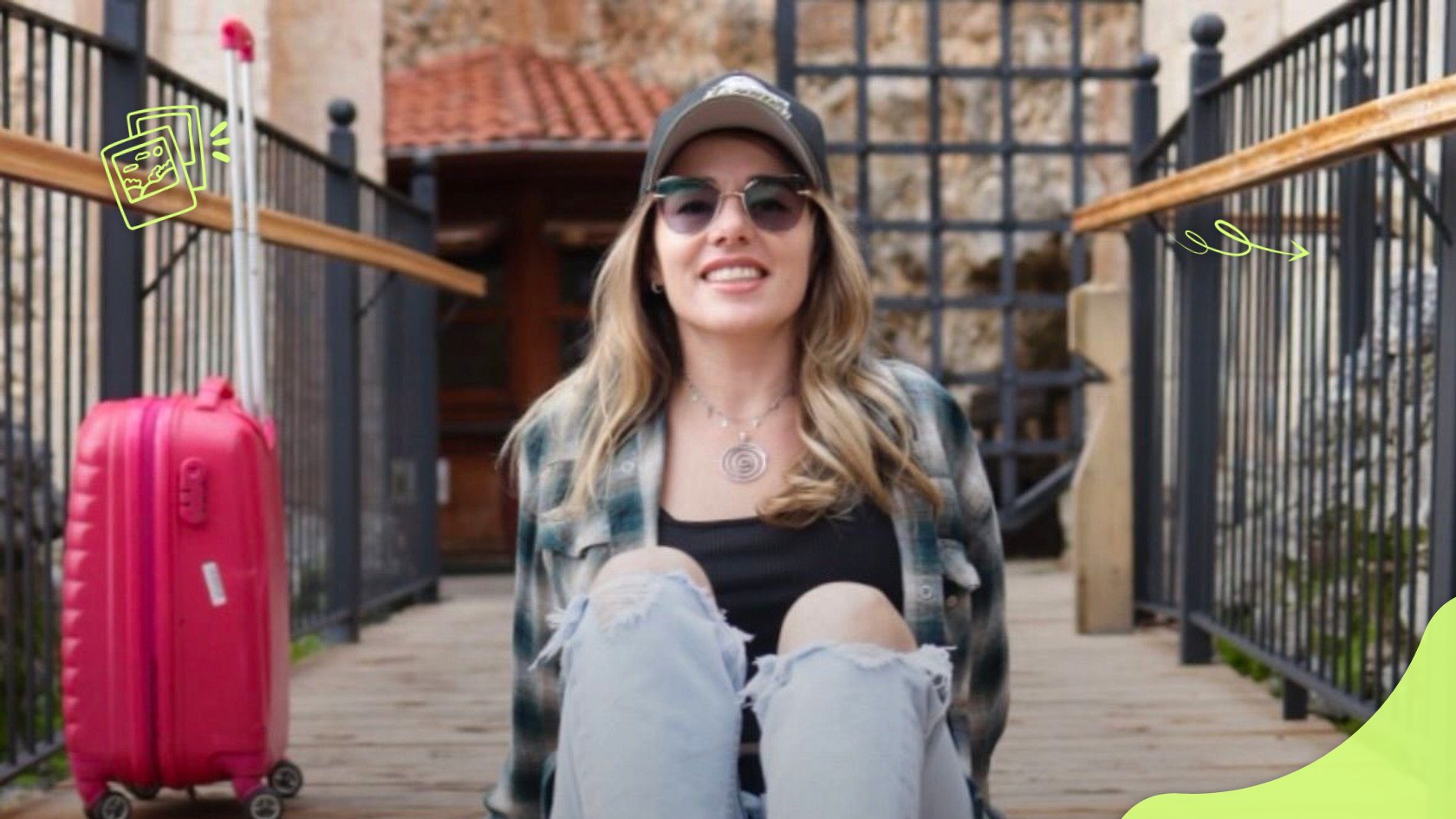 Катерина Нетеса сидить поруч із рожевою валізою ручної поклажі на коліщатах