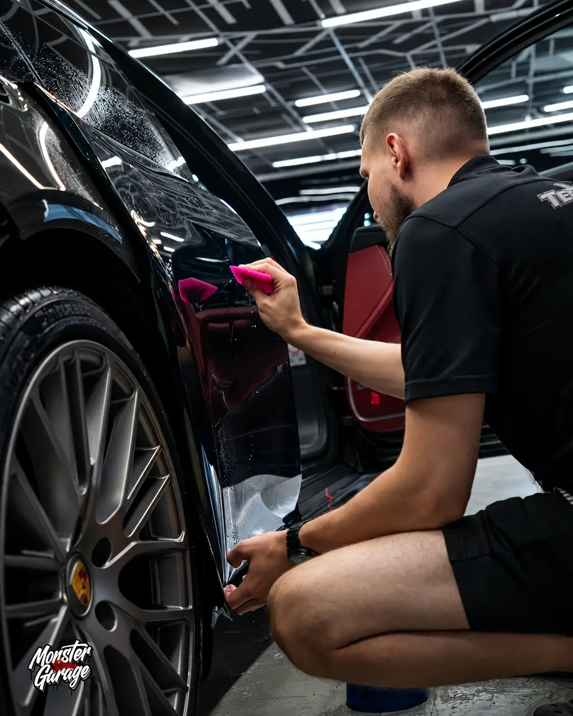 Мастер работает с плёнкой на изгибе заднего крыла Porsche у колёсной арки