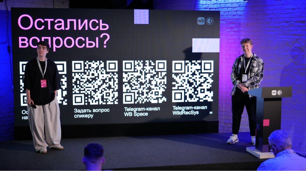 Сцена гибридного митапа с большим экраном трансляции и спикером на сцене