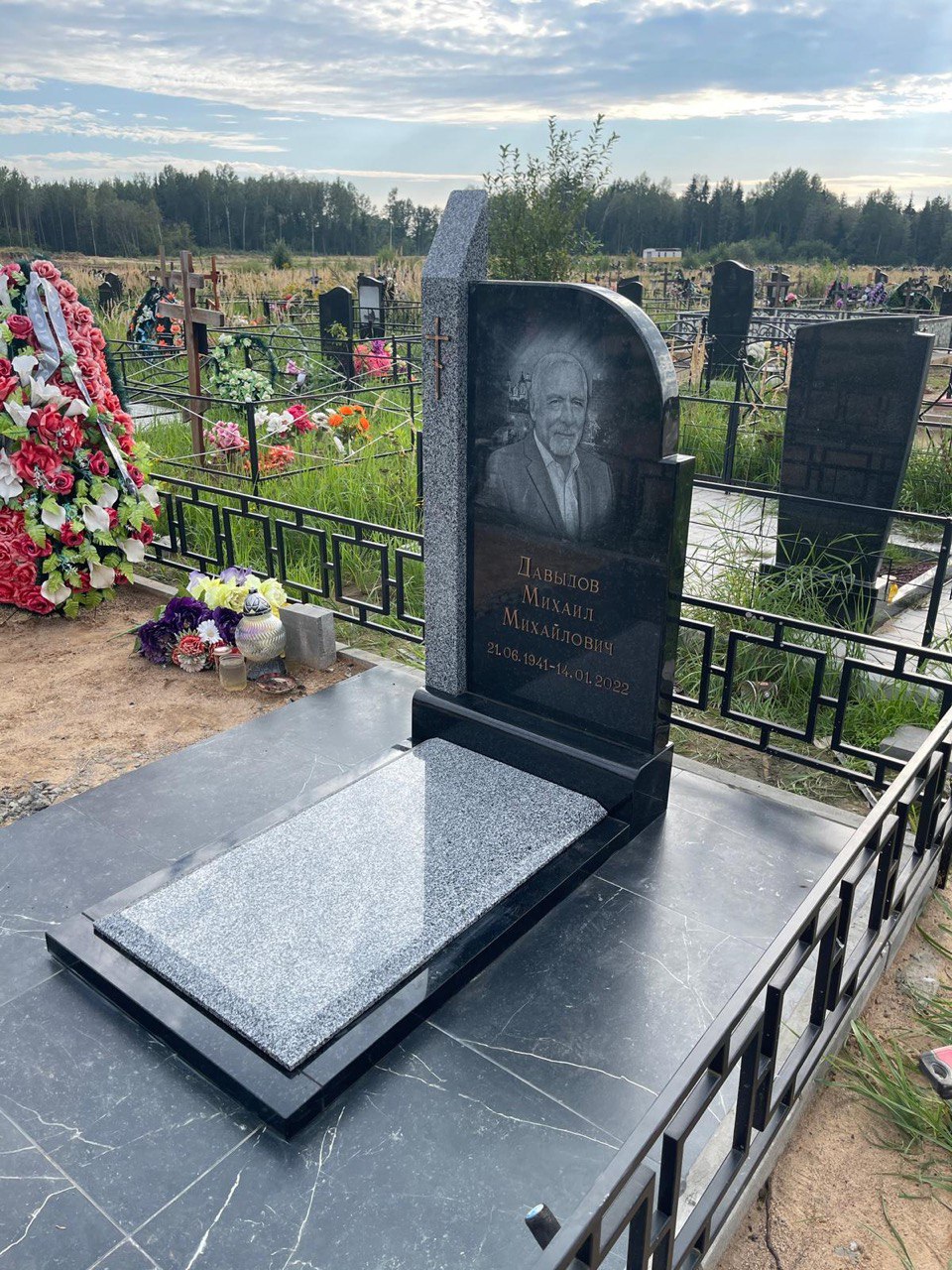 Памятник из чёрно-серого гранита с металлической оградой