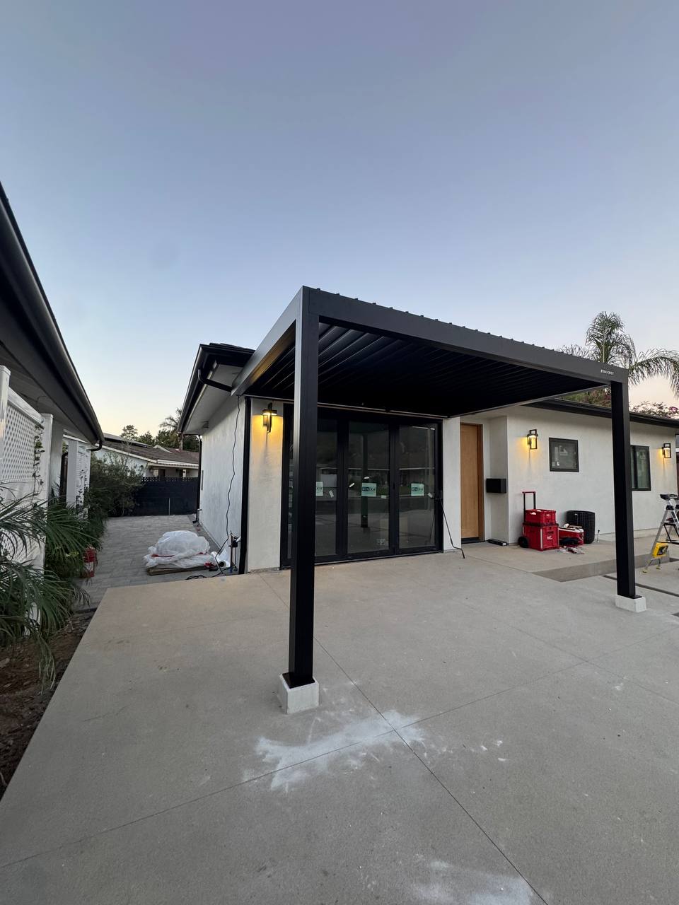 Wide view of the completed two-post black pergola outside the house.