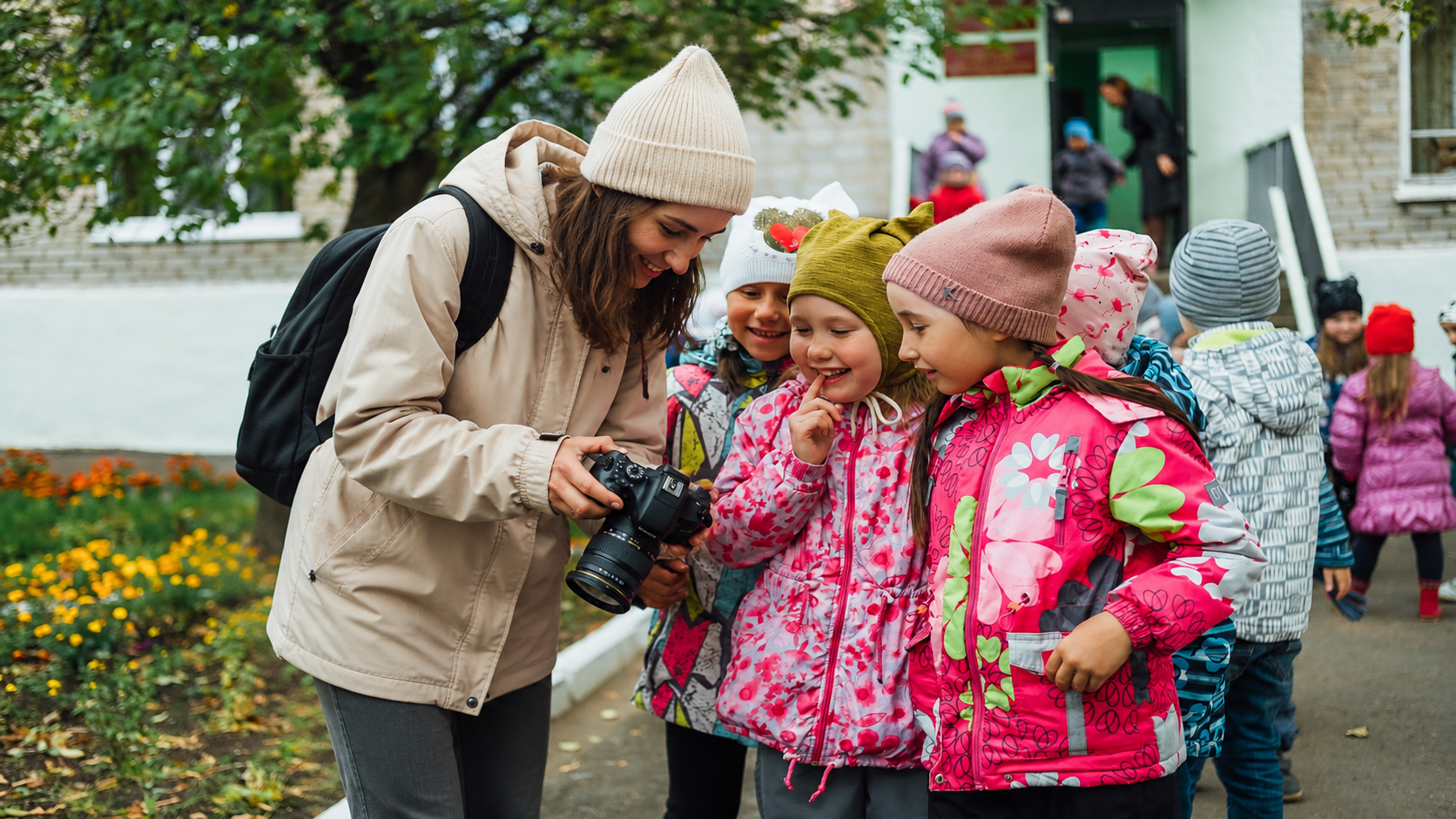 Photographer showing camera to schoolchildren outdoors