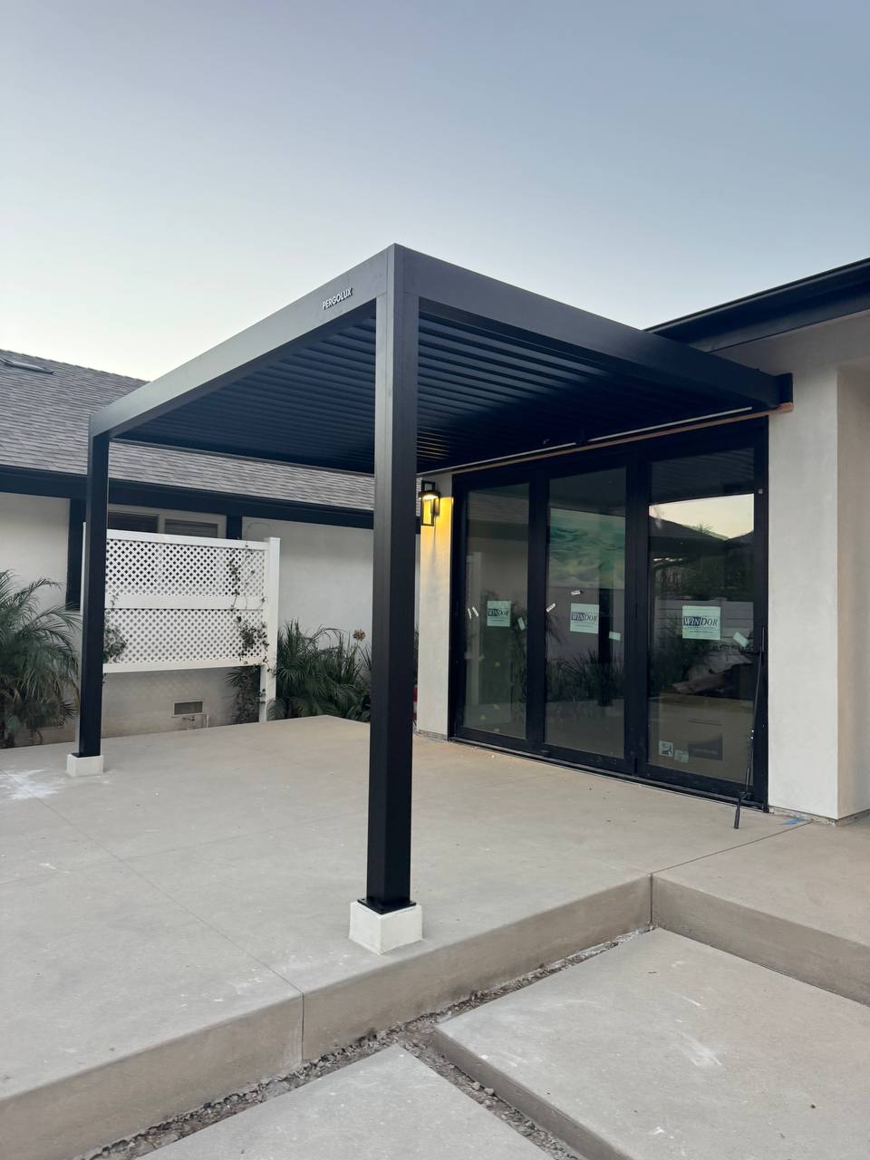 Corner view of the wall-mounted black pergola beside the glass patio doors.