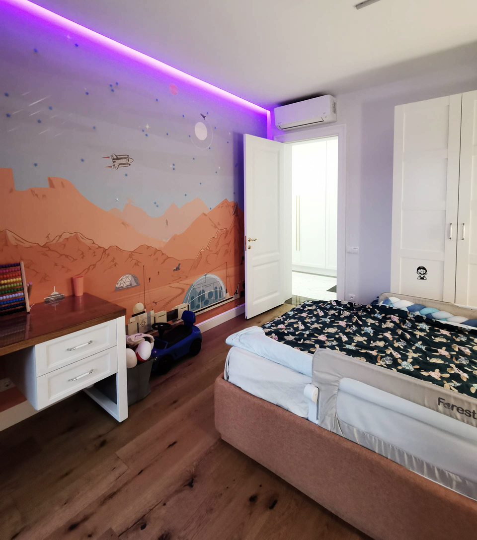 детские фотообои с изображение гор, сиреневая подсветка за потолком, деревянный пол, белый стол, кровать