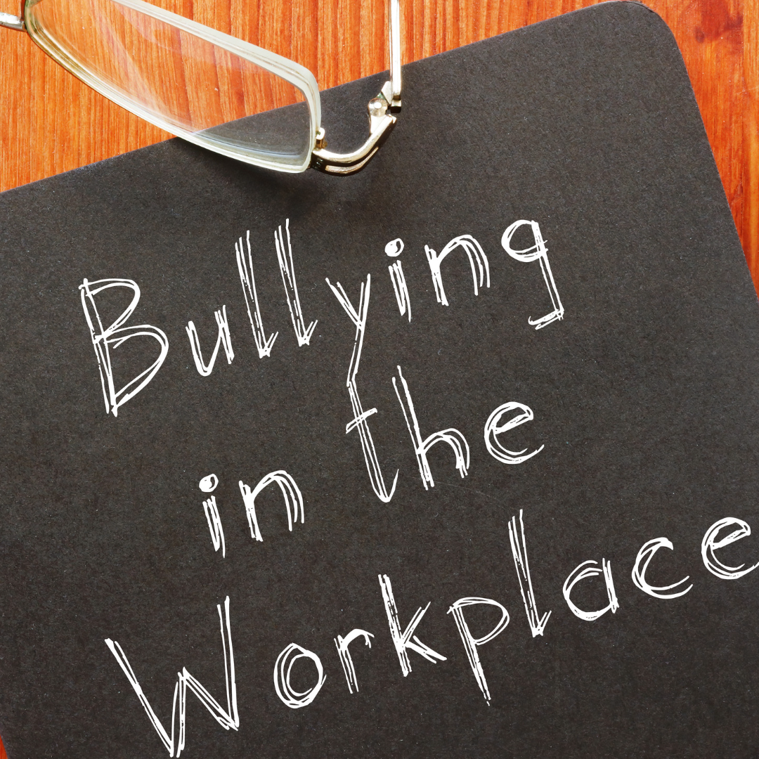 Paper with glasses above it with the words bullying in the workplace written on iut.