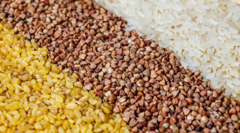 Крупный план гречки, риса и пшеничной крупы, разложенных слоями на поверхности, иллюстрация рынка зерновых культур.