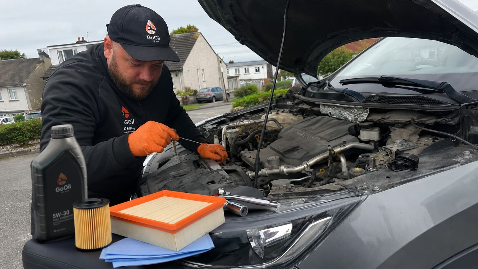Mobile mechanic checking the engine of a Nissan with the bonnet open during a car service at a customer's home