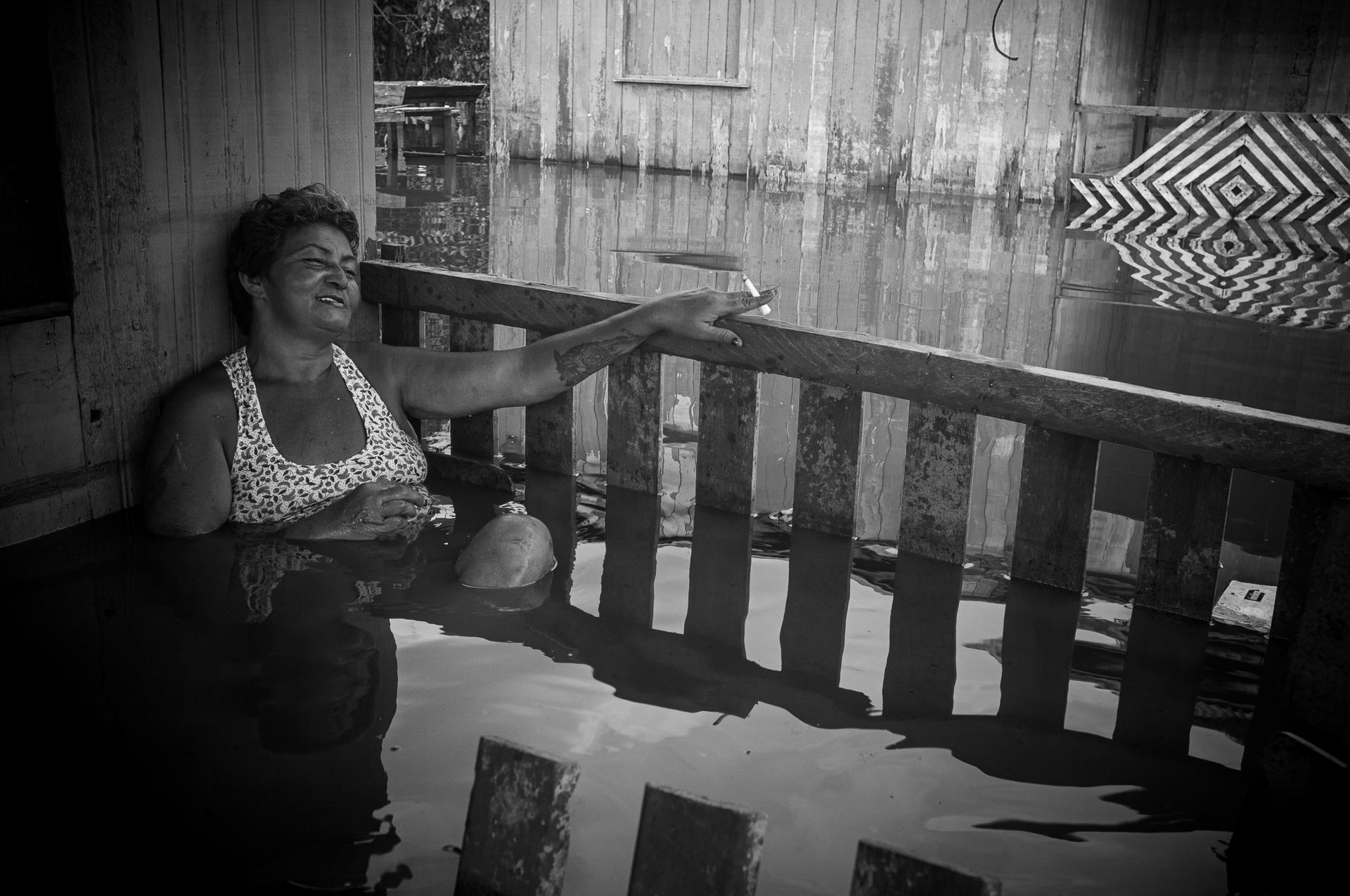 Brazil | Ricardo Funari Di Lucia. Francisca Chagas takes a short break on the flooded veranda of her home between daily household tasks. 
