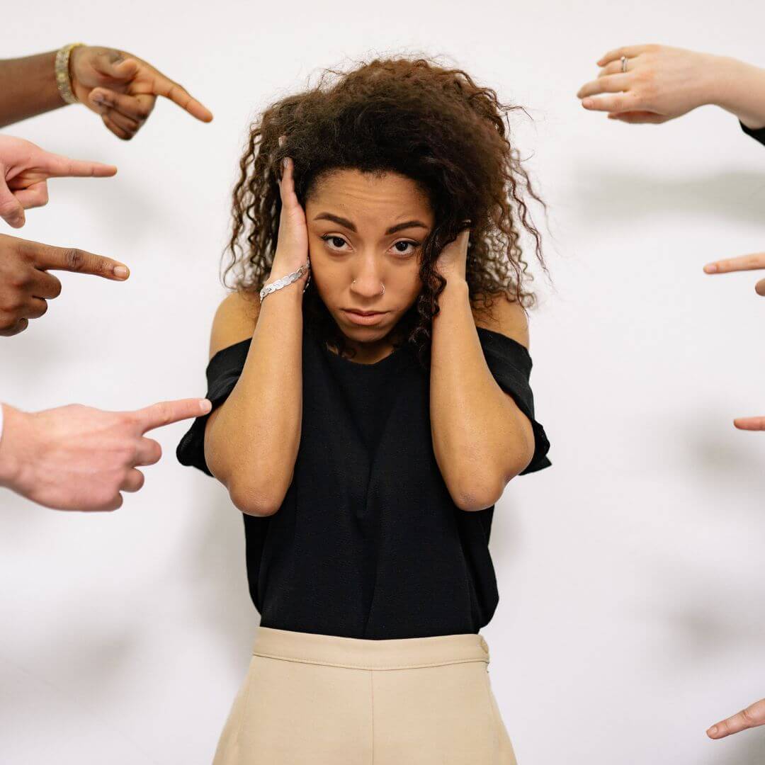 A person is surrounded by a group of people pointing their fingers at them.