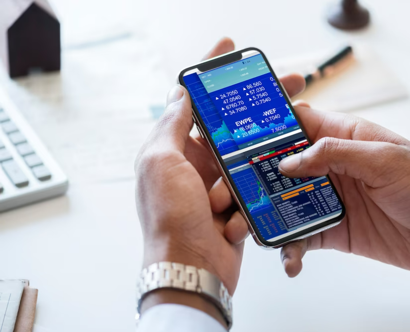 Manos sosteniendo un teléfono móvil con la interfaz de una de las mejores apps para trading.