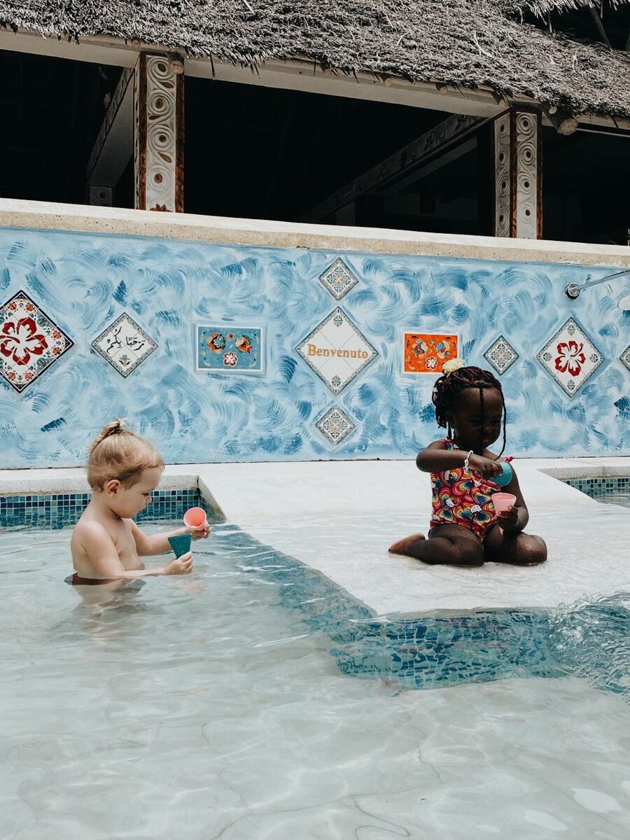 африканская девочка играет с русской девочкой в бассейне